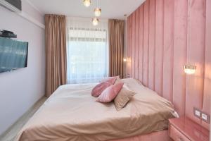 a bedroom with pink walls and a bed with two pillows at Apartamenty Jasny Brzeg in Władysławowo