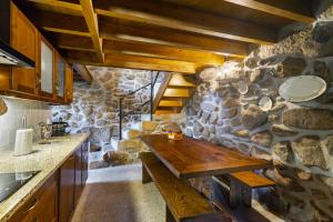 a kitchen with a stone wall and a wooden table at Isatour Casa na Serra in Adsamo +26 photos