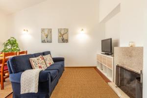 uma sala de estar com um sofá azul e uma televisão em Casa Nogueira - Minho's Guest em Pousadouros
