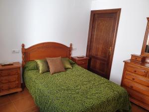 a bedroom with a bed with a green comforter at Alojamiento Rural Mirador del Valle in Baños de la Encina