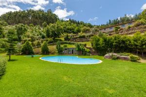 uma piscina num jardim relvado com árvores e edifícios em Casa Nogueira - Minho's Guest em Pousadouros