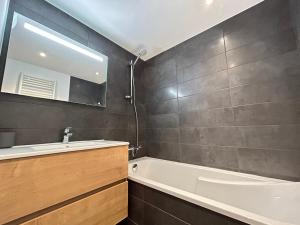 une salle de bain avec une baignoire, un lavabo et un miroir dans l'établissement Appartement 4 Chambres au Coeur des Gets - Haut Standing, Parking, Wifi, Balcon, Proche Commerces - FR-1-623-319, aux Gets