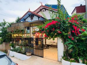 a house with red flowers and a black gate at Pết house Mộc Châu in Mộc Châu