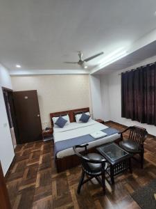 een slaapkamer met een bed, een tafel en een stoel bij Hotel Aerotech Suite in New Delhi