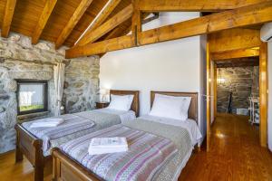 2 camas en una habitación con una pared de piedra en Isatour Casa na Serra, en Adsamo