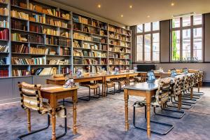 biblioteca con mesas, sillas y estanterías en Les Maisons de Lea, a member of Radisson Individuals en Honfleur