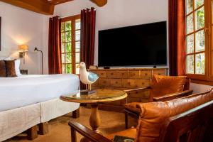 a bedroom with a bed and a tv and a table at Les Maisons de Lea, a member of Radisson Individuals in Honfleur
