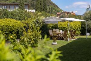 a table and chairs under an umbrella in a garden at Carly's Rooms in Nago-Torbole