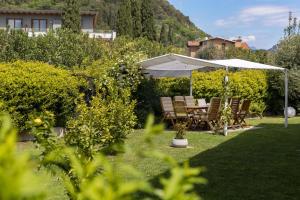 - une table et des chaises sous un parasol dans le jardin dans l'établissement Carly's Rooms, à Nago-Torbole