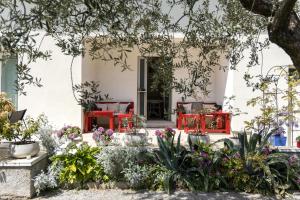 a garden with red chairs and flowers in front of a building at Carly's Rooms in Nago-Torbole