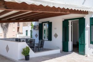a white house with green shutters and a patio at Le Case di Franca in Trapani