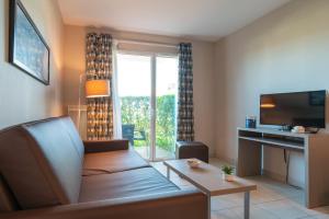 un soggiorno con divano, scrivania e finestra di Les Thermes 508 - Appt avec piscine partagée a Concarneau