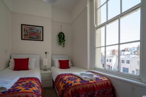 two beds in a room with a window at Montpellier Regency apartment balcony & parking in Cheltenham