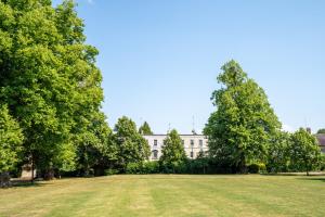 a large grass field in front of a white building at Montpellier Regency apartment balcony & parking in Cheltenham