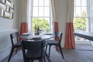 ein Esszimmer mit einem Tisch, Stühlen und Fenstern in der Unterkunft Montpellier Regency apartment balcony & parking in Cheltenham