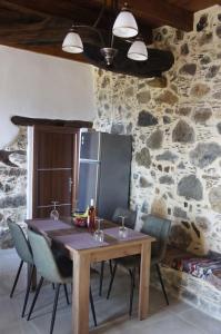 Alegria stone house في AmigdhalokeFálion: طاولة غرفة طعام مع كراسي وجدار حجري