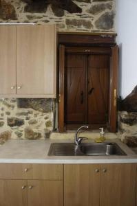 a kitchen with a sink and a stone wall at Alegria stone house in AmigdhalokeFálion