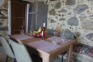 a wooden table with a bowl of bananas and a bottle of wine at Alegria stone house in AmigdhalokeFálion