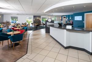 a restaurant with a bar and tables and chairs at Holiday Inn Express Lichfield, an IHG Hotel in Lichfield