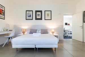 a white bedroom with a white bed and two tables at Carly's Rooms in Nago-Torbole