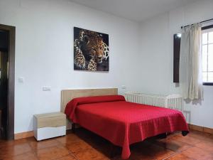um quarto com uma cama com um cobertor vermelho em Cortijo Puente Alhama em Alhama de Granada