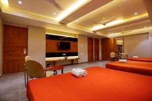 pokój hotelowy z 2 łóżkami i telewizorem w obiekcie HOTEL OM w mieście Somnath
