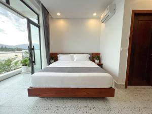 a bedroom with a bed and a large window at The Rivera Kampot in Kampot