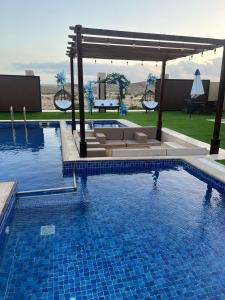 a swimming pool with a gazebo and a swimming pool at Blue Revan chalet in Salalah