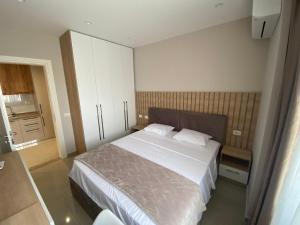 1 dormitorio con 1 cama grande con sábanas blancas en Olivia's Apartments, en Velipojë