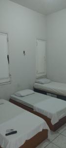 two beds in a white room with two windows at San Luis in São Luís