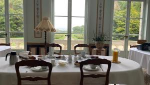 a dining room with a table with chairs and windows at Château de Praslins in Nogent-sur-Vernisson