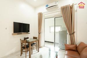 a living room with a table and a tv at Merry House Bạch Dương in An Khê