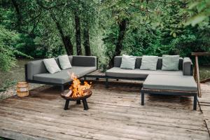 zwei Sofas und eine Feuerstelle auf einer Holzterrasse in der Unterkunft Goat's Paradise in Bohinj