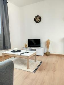 a living room with a coffee table and a tv at Le Pampas - ZMN Conciergerie in Saint-Quentin