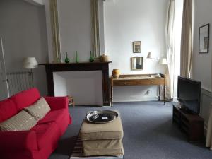 a living room with a red couch and a tv at Hôtel Saint Laurans in Aurignac