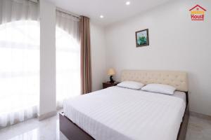 Un dormitorio blanco con una cama grande y una ventana en Merry House Bạch Dương, en An Khê
