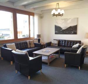 ein Wohnzimmer mit einem Sofa, Stühlen und einem Tisch in der Unterkunft Hotel Jungfrau Mürren in Mürren