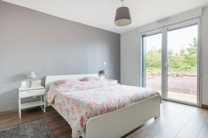 a white bedroom with a bed and a window at La grange de Merlin in Concoret