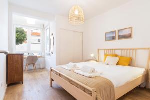 ein Schlafzimmer mit einem Bett mit weißen Laken und einem Schreibtisch in der Unterkunft Oeiras Apartment in Oeiras