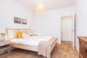 Schlafzimmer mit einem Bett mit weißer Bettwäsche und gelben Kissen in der Unterkunft Oeiras Apartment in Oeiras + 3 Fotos