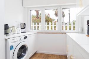 a white laundry room with a washer and dryer at Oeiras Apartment in Oeiras