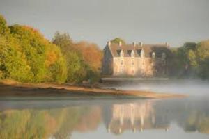 a castle sitting on top of a body of water at La grange de Merlin in Concoret