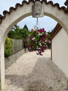 einen Torbogen mit einem hängenden Korb mit rosa Blumen in der Unterkunft Maison atypique avec un grand terrain !animaux bienvenus !wifi netflix écran plat 4k in Les Forges