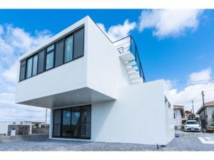 uma casa branca com escadas ao lado em Nashiro White Cube - Vacation STAY 14460 em Itoman