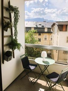 balcón con mesa, sillas y ventana en Paisible studio avec agréable loggia 2 mn du centre, en Aix-les-Bains