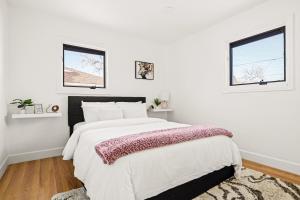 a white bedroom with a large bed and two windows at New Colorful Home - Backyard Oasis - City Park in Denver