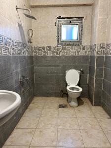 a bathroom with a toilet and a sink and a window at مبيت Mabeet - شقق ستديو in 6th Of October
