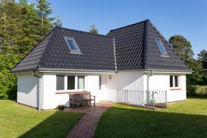a white house with a black roof at Das kleine Haus - Reetdachhaus Petersen in Nebel