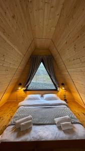 ein großes Bett in einem Holzzimmer mit Fenster in der Unterkunft AURA Cottages in Kazbegi