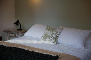 a bed with two pillows and a lamp on a table at Estancia La Titina, Posada y Reserva Natural in Concepción del Uruguay